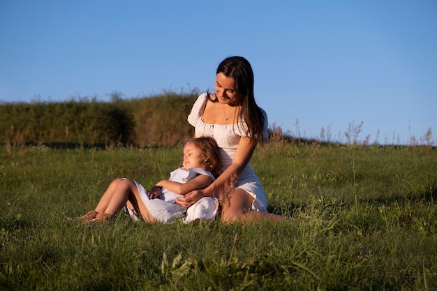 Full shot woman and girl sitting outdoors