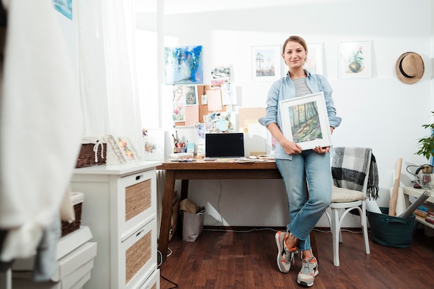 Free photo full shot of woman holding artwork