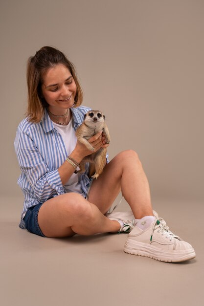 Full shot woman holding meerkat