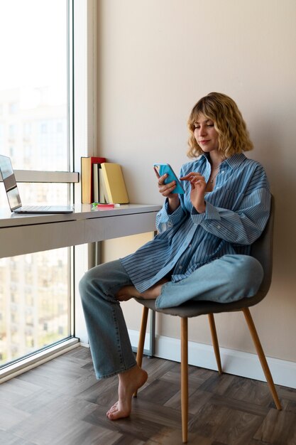 Full shot woman holding smartphone