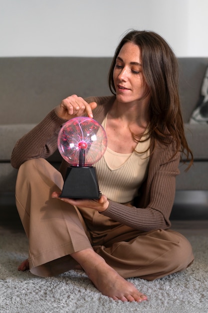 Full shot woman interacting with a plasma ball