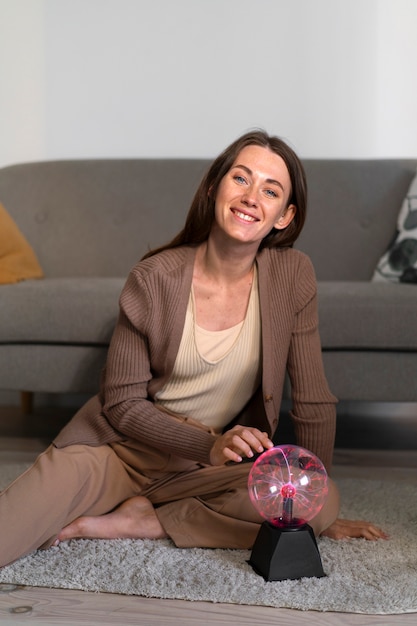 Full shot woman interacting with a plasma ball