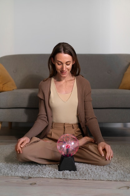 Full shot woman interacting with a plasma ball