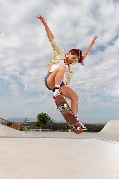 Full shot woman jumping with skateboard