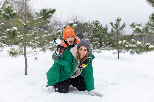 Full shot woman and kid playing with snow