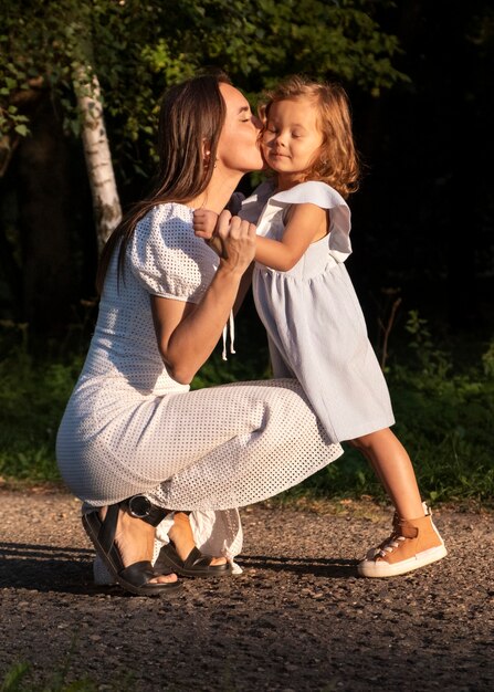 Full shot woman kissing girl on cheek