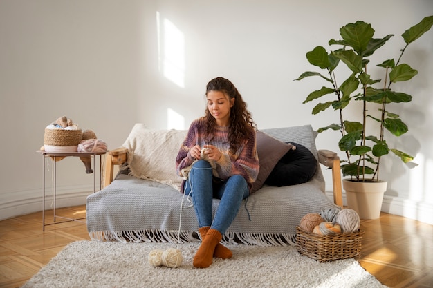 Free photo full shot woman knitting at home