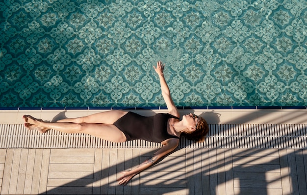 Full shot woman laying near pool