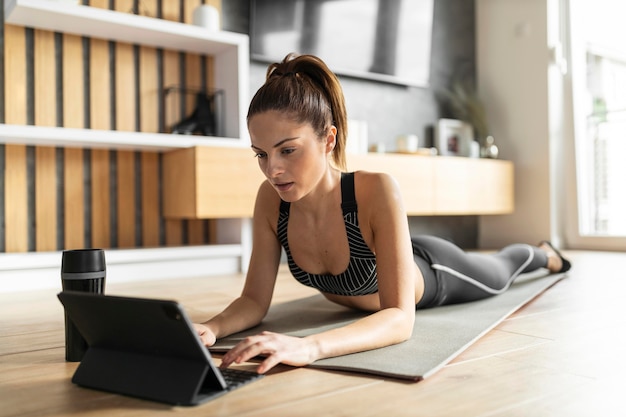 Free photo full shot woman on mat with tablet