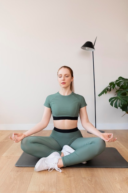 Full shot woman meditating on mat