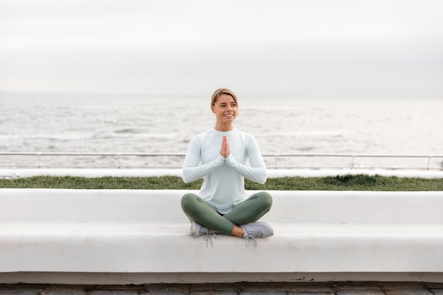 Free photo full shot woman meditating outdoors