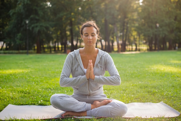 Full shot woman meditating on yoga mat