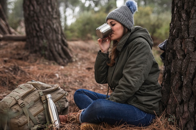 Full shot woman near tree drinking