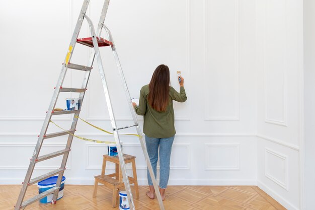 Full shot woman painting wall