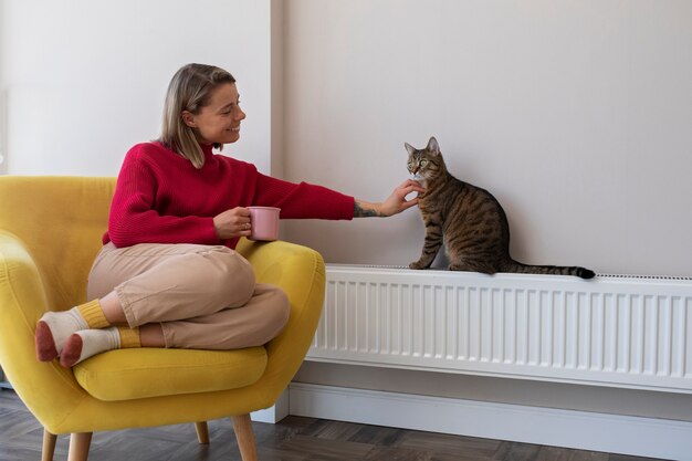 Full shot woman petting cute cat