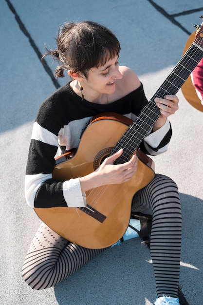 Full shot woman playing the guitar