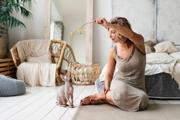 Free Photo full shot woman playing with hairless cat