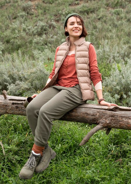 Full shot woman posing sitting on log