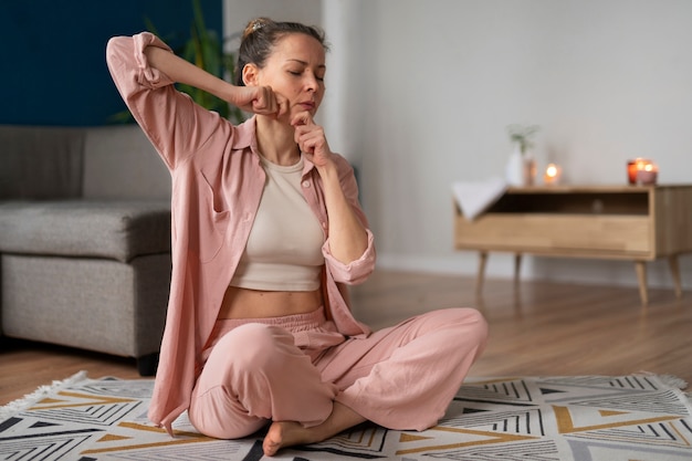 Full shot woman practicing facial yoga