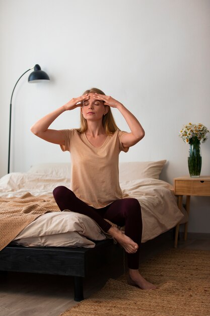 Full shot woman practicing facial yoga