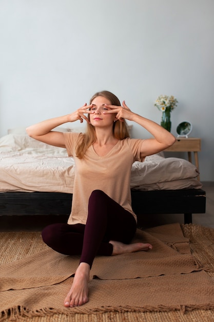 Full shot woman practicing facial yoga