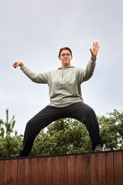 Full shot woman practicing tai chi outdoors