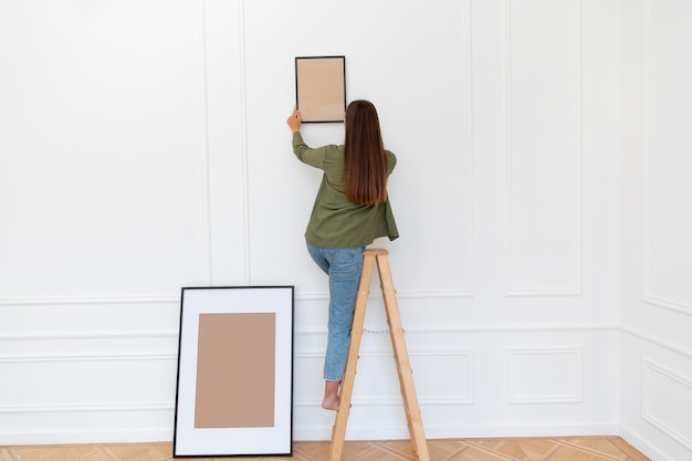 Free Photo full shot woman putting frame on wall