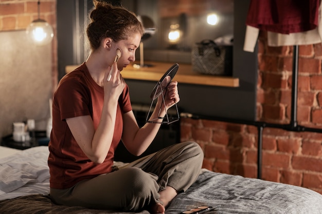 Free Photo full shot woman putting on makeup in bedroom