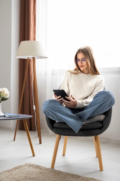 Full shot woman reading digital magazine