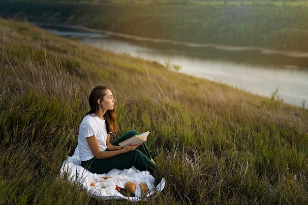 Free photo full shot woman reading in nature