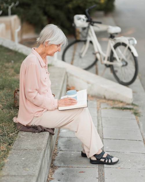 Full shot woman reading outdoors