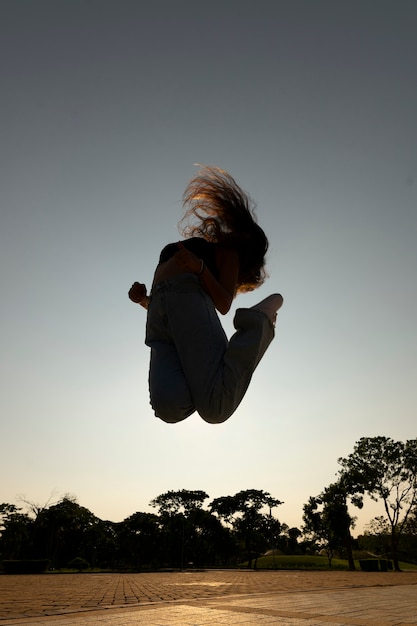 Full shot woman silhouette jumping at sunset