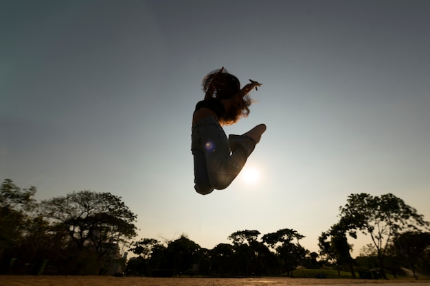 Full shot woman silhouette jumping at sunset