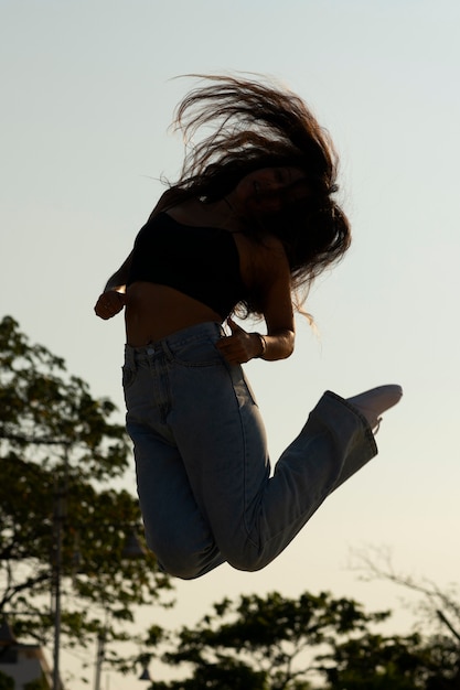 Full shot woman silhouette jumping at sunset