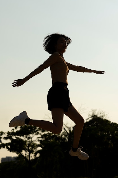 Full shot woman silhouette jumping at sunset