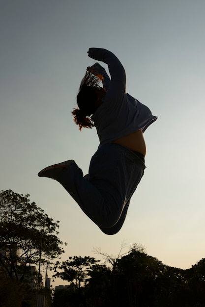 Full shot woman silhouette jumping at sunset