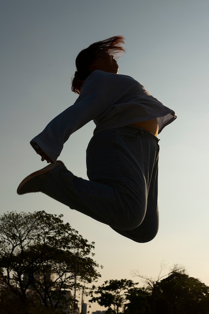 Full shot woman silhouette jumping at sunset