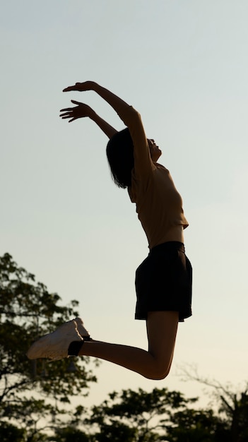 Full shot woman silhouette jumping at sunset