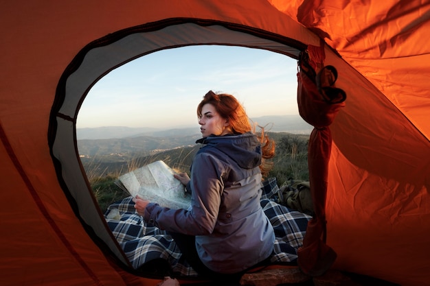 Full shot woman sitting near tent