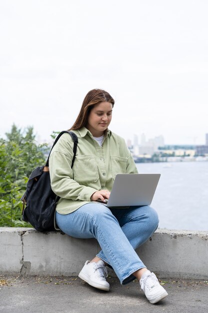 Full shot woman sitting with laptop