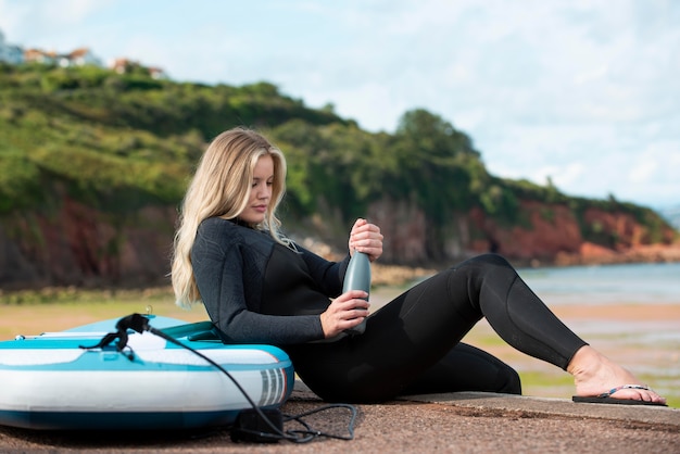 Free photo full shot woman sitting with paddleboard