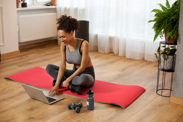 Full shot woman sitting on yoga mat