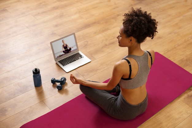 Full shot woman sitting on yoga mat