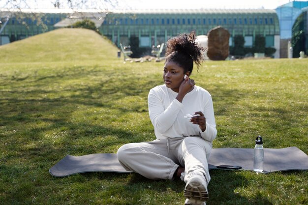 Full shot woman sitting on yoga mat