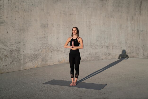 Full shot woman standing on yoga mat