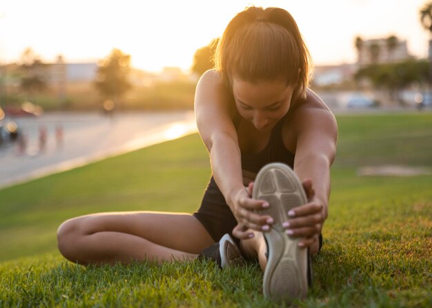 Full shot woman stretching her leg