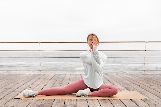 Free Photo full shot woman stretching on mat