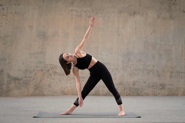 Free Photo full shot woman stretching on mat