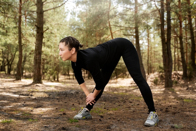 Full shot woman stretching in nature