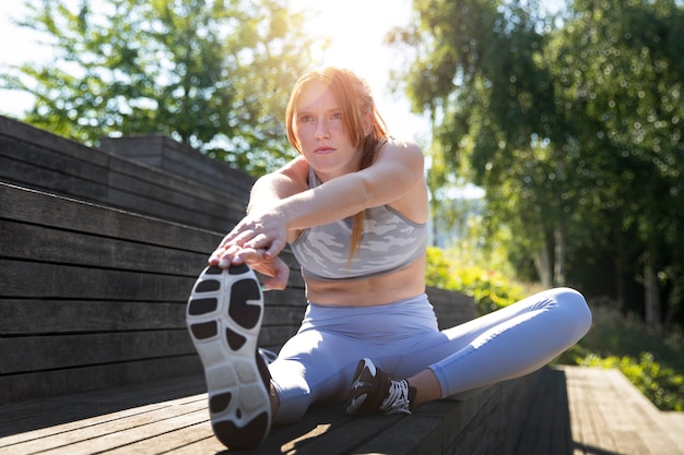 Free photo full shot woman stretching outdoors